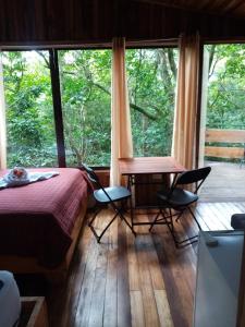 蒙泰韦尔德哥斯达黎加The Green Tree Lodge的一间卧室配有床和椅子以及大窗户