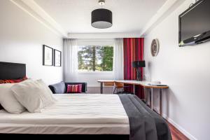 上维耶斯卡Hotel Käenpesä的一间卧室配有一张床、一张桌子和一个窗户。