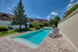 梅斯尼圣佩尔Logis Maison Gublin - Auberge du Lac的一座房子旁带两把椅子的游泳池
