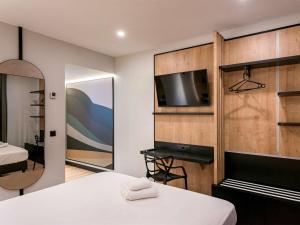菲格拉斯Ibis Styles Figueres Ronda的一间卧室配有一张床、一台电视和一面镜子