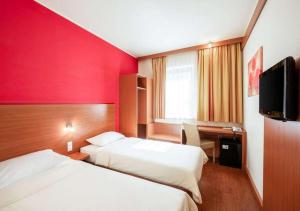 布达佩斯City Hotel Budapest的酒店客房设有两张床、一张桌子和一台电视。