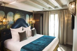 巴黎达芬奇酒店及Spa的一间卧室配有一张带蓝色和白色棉被的床