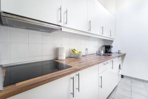 希欧福克City Home Balaton的厨房配有白色橱柜和木制台面