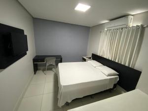 马卡帕玛卡帕巴酒店的一间卧室配有一张床、一张书桌和一台电视