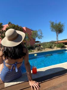 San Antonio de las MinasQuinta Lorame的坐在游泳池旁的戴帽子的女人