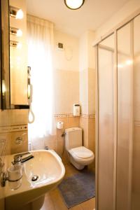 比萨罗马酒店的浴室配有白色卫生间和盥洗盆。