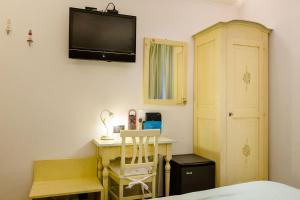 蒙特罗索阿尔马雷玛瑞娜酒店的一间卧室配有一张桌子和一台墙上的电视。