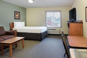 罗利WoodSpring Suites Raleigh Northeast Wake Forest的小型酒店客房配有1张床和电视。