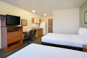 罗利WoodSpring Suites Raleigh Northeast Wake Forest的酒店客房设有两张床和一张书桌及电视