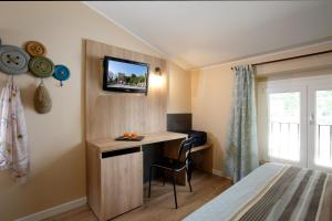 阿西西波尔塔努欧瓦酒店的一间卧室配有书桌,墙上配有电视