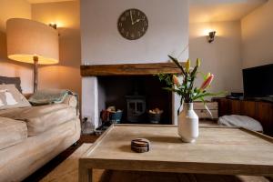 海菲尔德Sett Cottage的客厅配有咖啡桌和时钟