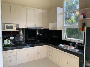 茂物Villa Sanlias的厨房配有白色橱柜和黑色台面