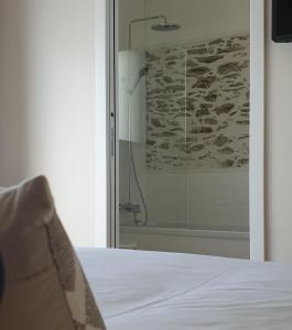 圣佩尔港Le Grand Jardin的一张床上,在房间里设有玻璃淋浴间