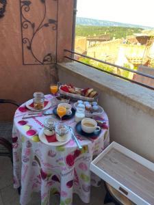 鲁西永Maison d'hôtes Une hirondelle en Provence的阳台上的桌子上摆放着食物和饮料