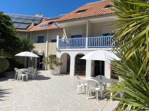 比斯卡罗斯海滩波浪之家酒店的房屋前设有带桌子和遮阳伞的庭院。
