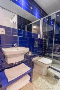 莱昂阿尔班尼旅馆的蓝色瓷砖浴室设有水槽和卫生间
