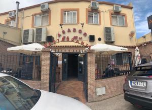 塞塞尼亚Hostal Seseña的一座建筑,设有通往带遮阳伞的餐厅的入口