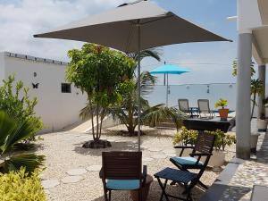 PoponguineAfrican Jaja villa Piscine-Climatisation的庭院配有椅子和桌子及遮阳伞