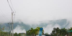 Ban Huai Phaiบ้านเอื้อมดาว เขาค้อ的远处的雾 ⁇ 山,有树木和汽车