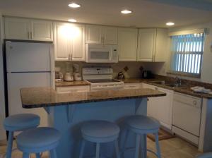 Point O'RocksIsland House Beach Resort 21的厨房配有白色橱柜和蓝色凳子