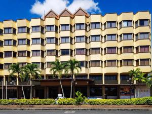 阿罗士打水晶大酒店的一座黄色的大建筑,前面有棕榈树