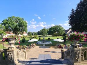 SzprotawaPałac Henryków的花园设有喷泉、桌子和遮阳伞