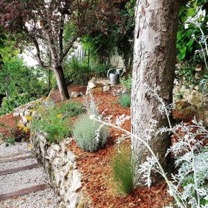瓦兹河畔欧韦全景酒店的一座花园,花园内种有树木,设有石墙