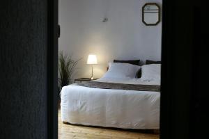 圣戈尔捷Les Oiseaux de Passage的一间卧室配有一张带白色床单和一盏灯的床。