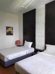 斯里巴加湾市昆普勒克吉拿27号酒店的两张位于酒店客房的床,配有两张sidx单人床