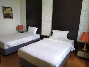 斯里巴加湾市昆普勒克吉拿27号酒店的配有白色床单的酒店客房内的两张床