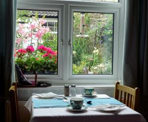 纳尔斯伯勒基尔克加特之屋酒店的一张桌子,有两杯,两扇窗户,有鲜花