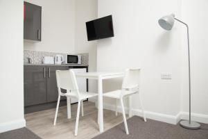 贝肯翰姆TLK Apartments & Hotel - Beckenham High Street的厨房配有白色的桌子和白色的椅子