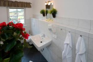 萨尔茨堡Apartments Ante Portas的白色的浴室设有水槽和红色的鲜花