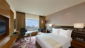 斋浦尔斋浦尔市中心假日酒店的酒店客房配有一张床、一张书桌和一台电视。