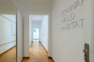 巴登-巴登Schwarzwald Loft的走廊设有白色墙壁、木地板和镜子