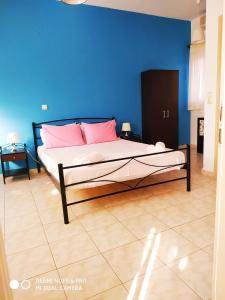 阿尔戈斯托利翁Apartments Onar的一间卧室配有带粉红色枕头的床和蓝色的墙壁