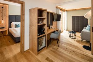 卡尔达罗Lake Spa Hotel SEELEITEN的酒店客房带一张床铺、一张书桌和一间卧室
