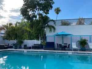 基韦斯特棕榈酒店的游泳池配有桌子、遮阳伞和椅子