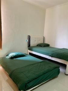 NalagatAnugrah Inn的配有绿床单的客房内的两张床