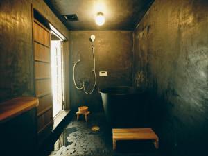 笛吹市古民家宿るうふ 澤之家的一间带浴缸和淋浴的浴室以及窗户。