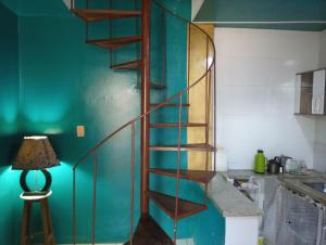 瓜拉派瑞Casa de praia; Itapebussu, Guarapari, ES.的一个带灯的厨房内的木制螺旋楼梯