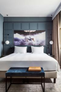 马德里马德里普拉多丽笙酒店的一间卧室配有一张大床和蓝色长凳
