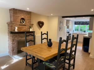 WarcopThe Cosy Nook Cottage Company - Cosy Cottage的厨房以及带木桌和壁炉的用餐室。