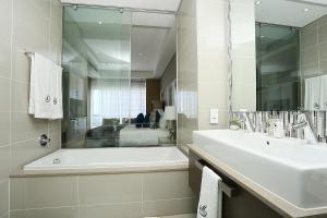 约翰内斯堡305 Sandton Skye的白色的浴室设有浴缸和水槽。