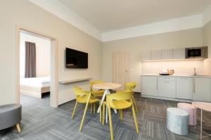 奥洛穆茨SLADOVNA Apartments的厨房以及带桌子和黄色椅子的用餐室。