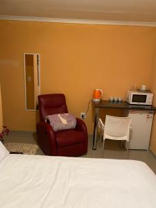 波罗瓜尼Mankweng lodge的一间卧室配有一张床、一把椅子和一台微波炉