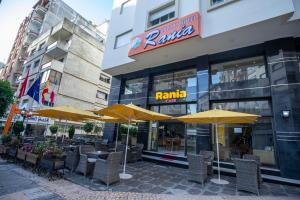 丹吉尔Appart Hotel Rania的大楼前的餐厅,配有椅子和遮阳伞
