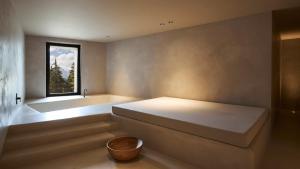 布列瑟农Forestis Dolomites的一间卧室设有一张床、一个窗口和一个浴缸