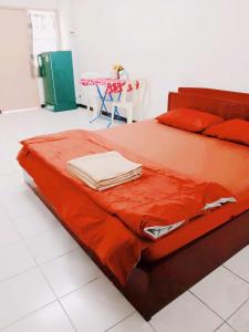 曼那Pacific Apt的一张带橙色床单的床和一张桌子