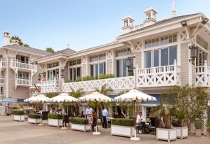洛杉矶百叶窗海滩酒店的一座大建筑前面设有桌子和遮阳伞